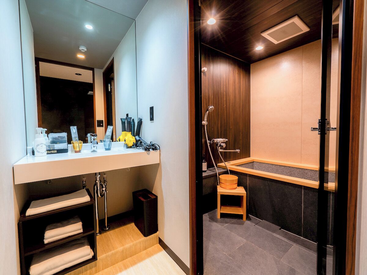 A modern bathroom with a vanity, mirror, and shower area.