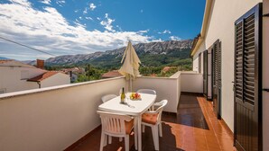 Ein Balkon mit einem Tisch für zwei Personen, einer Weinflasche und einer Obstschale.
