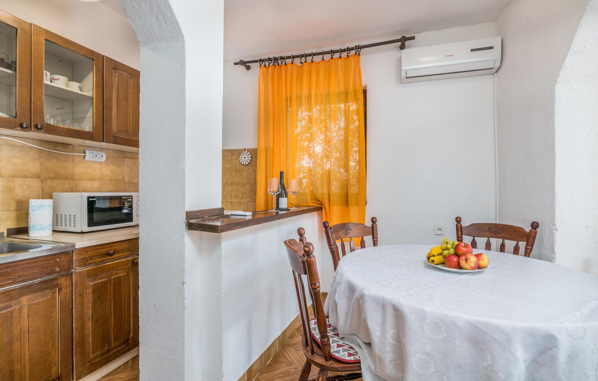 Una cucina compatta con mobili in legno, un forno a microonde e un'area pranzo con un tavolo apparecchiato per due.