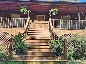 A wooden staircase leading to a wooden building with a lattice fence and potted plants. - Stay Together! Mini farm escape, sleeps 10, Hot tub, covered porches (Pembroke)