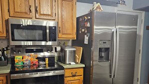 Una cocina con armarios de madera, electrodomésticos de acero inoxidable y un refrigerador con imanes.