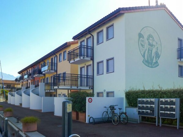 Ein mehrgeschossiges Wohngebäude mit Balkonen, einem Wandgemälde an der Seite und einem Fahrrad davor.