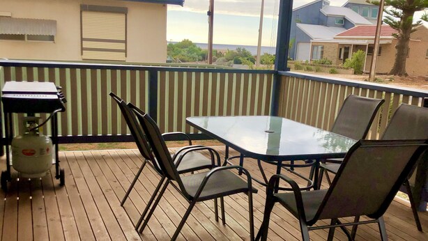 An outdoor patio with a table and chairs, a barbecue grill, and a gas cylinder.