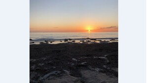 A beach at sunset with a clear sky.