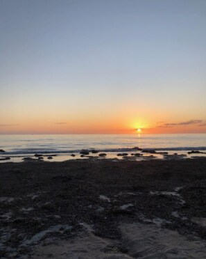 Una spiaggia al tramonto, con cielo sereno.