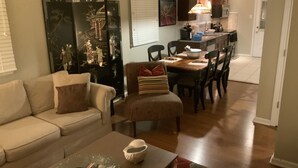 A living room with a sofa, a coffee table, and a dining area with chairs and a table.