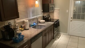 A kitchen with a sink, stove, oven, and cabinets.
