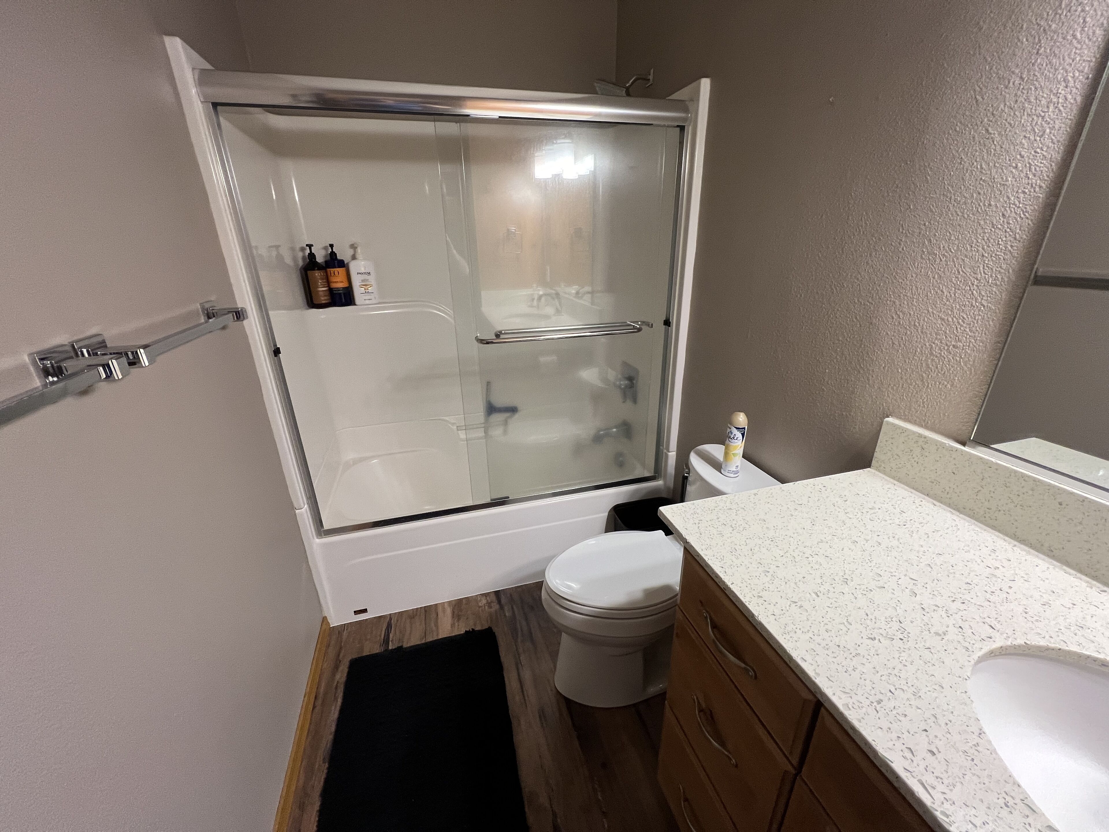 Un bagno moderno con doccia vetrata, un WC bianco e un mobile vanitario in legno con piano bianco.