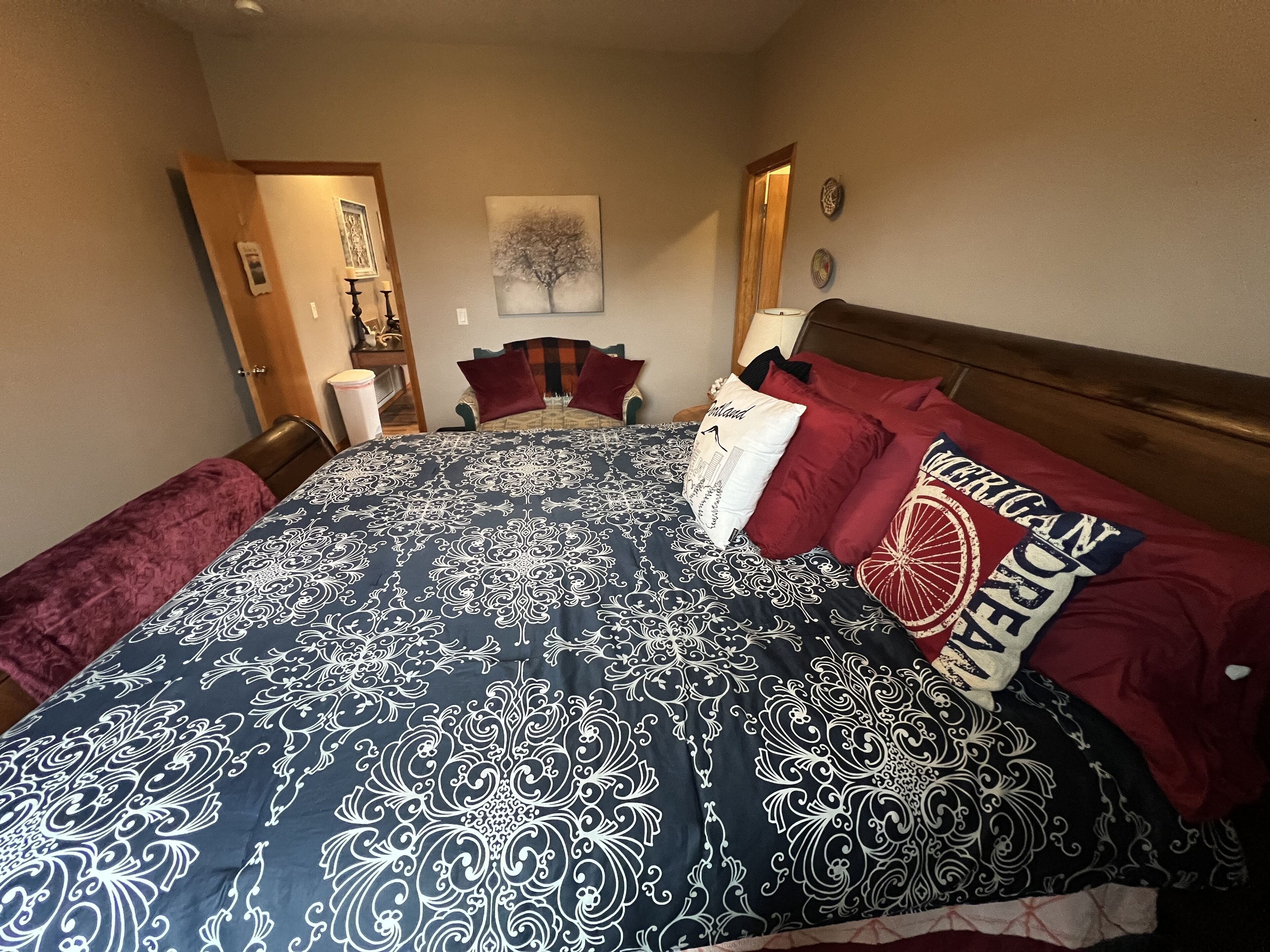 A bedroom with a large bed, a wooden headboard, a nightstand, a lamp, and a framed picture on the wall.