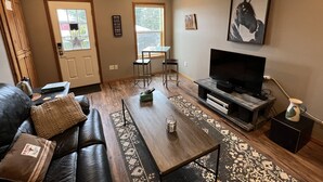 A living room with a sofa, coffee table, TV, and a fireplace. - Wounded Knee Ranch at the Red Hills. Full separate and private suite with deck (Newberg)