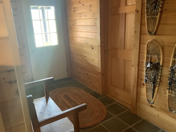 A wooden interior with a door, a window, and a table with a chair.