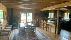 Interior de uma cabana de madeira com área de jantar, cozinha e bar.