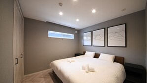 A bedroom with a large bed, a window, and three framed pictures on the wall. - Cherrywoods Place (Hakuba)
