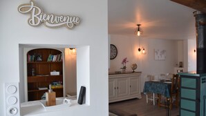 Una sala de estar con chimenea, una estantería y un comedor con mesa y sillas.