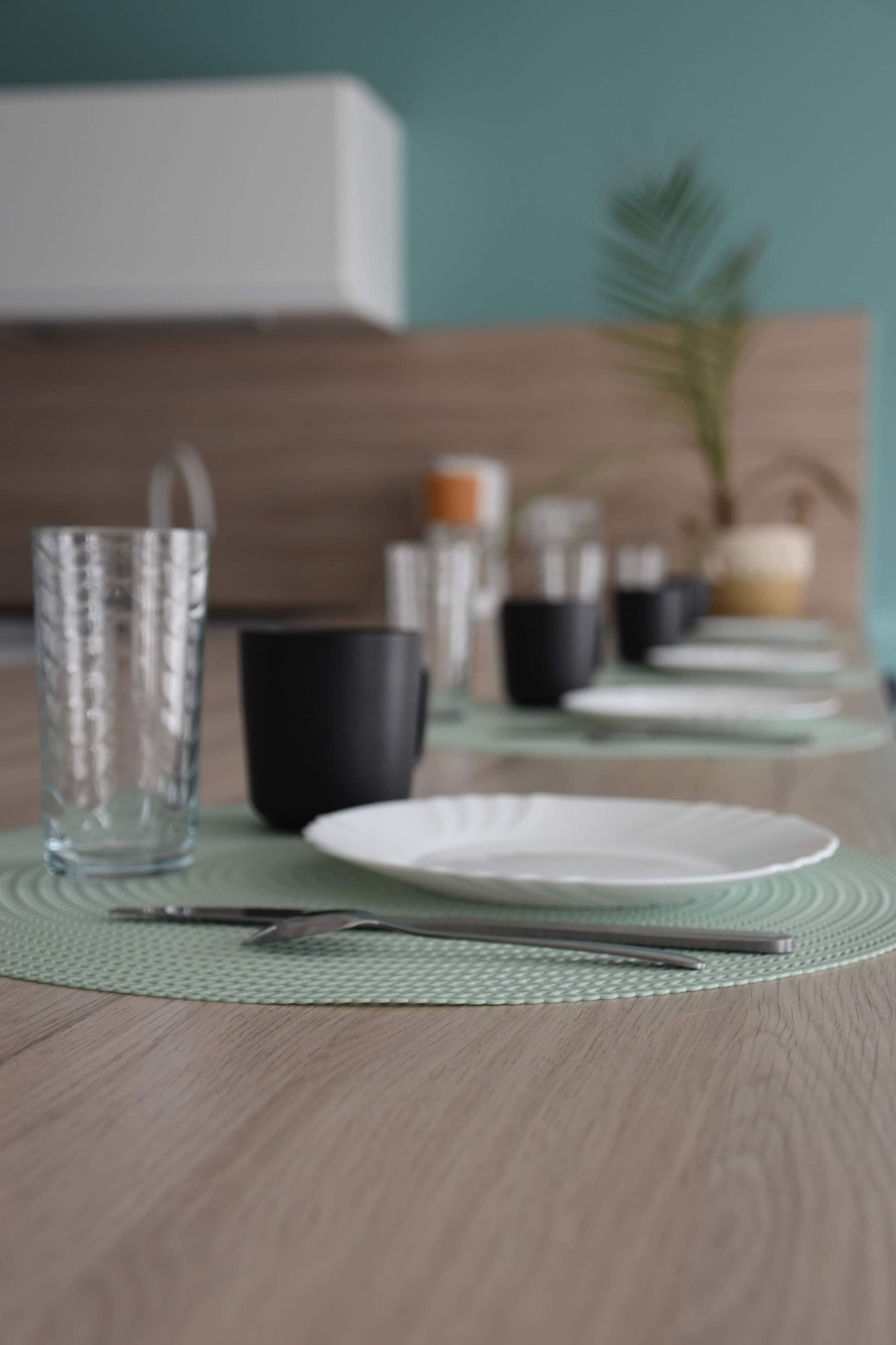 A dining table with plates, cutlery, and glasses set for a meal.