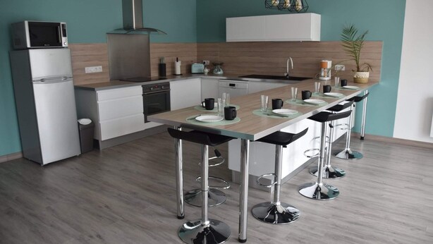 Una cocina moderna con una isla central, taburetes de bar y un microondas sobre el refrigerador.