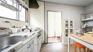A kitchen with a sink, dish rack, cabinets, and a dining area with a table and chairs. - Guest House MEETS Okayama (Okayama)
