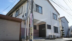 A two-story building with a garage door, a small entrance, and a "MEETS" sign on the front door. - Guest House MEETS Okayama (Okayama)