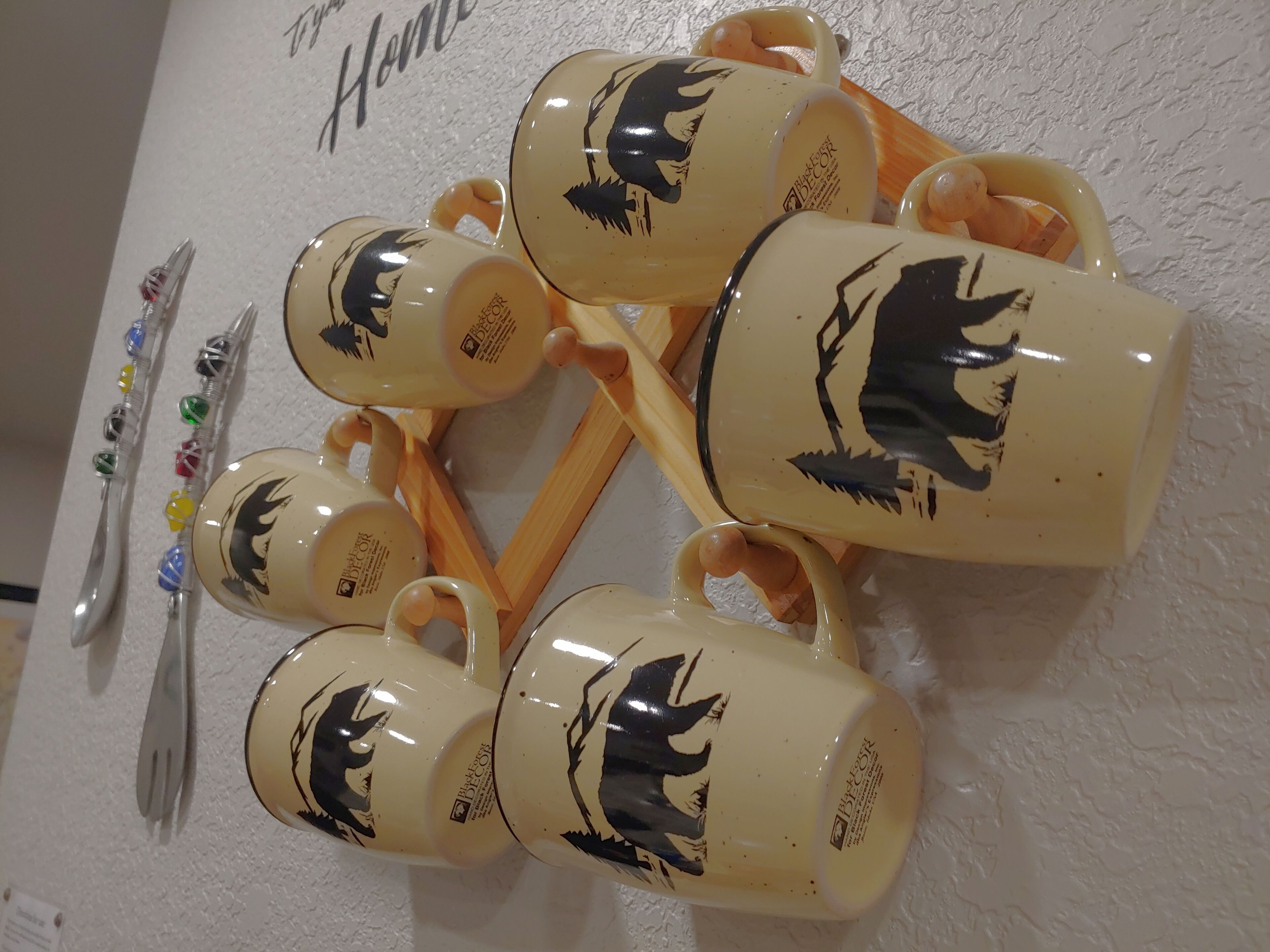 Conjunto de canecas de cerâmica com desenho de lobo, dispostas numa parede branca com textura.