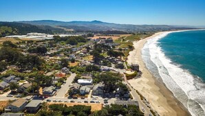 Vista aérea de una zona residencial costera con casas, una playa y un cielo azul despejado.