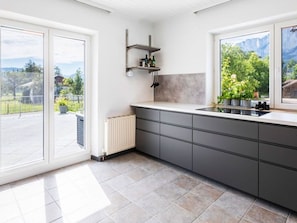 A modern kitchen with a large window, a built-in stove, and a countertop.