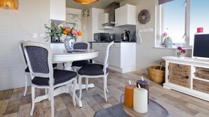 A modern kitchen with white cabinets, a dining table with two chairs, and a large window with a view. - Nice apartment in Bruinisse (Bruinisse)