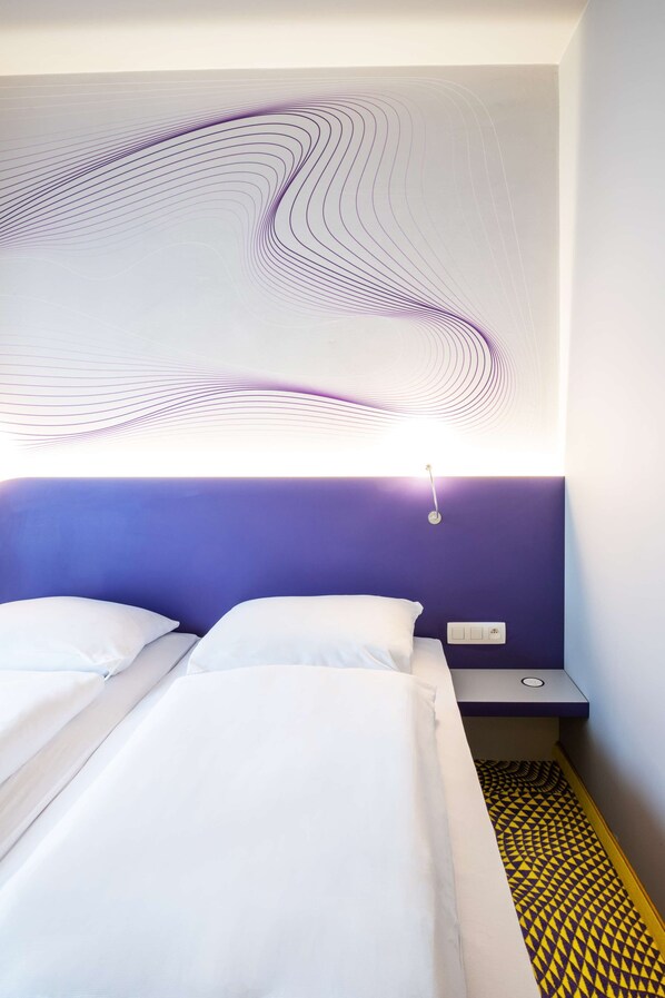 Quarto de hotel moderno com uma cama grande, cabeceira com design ondulado e piso estampado.