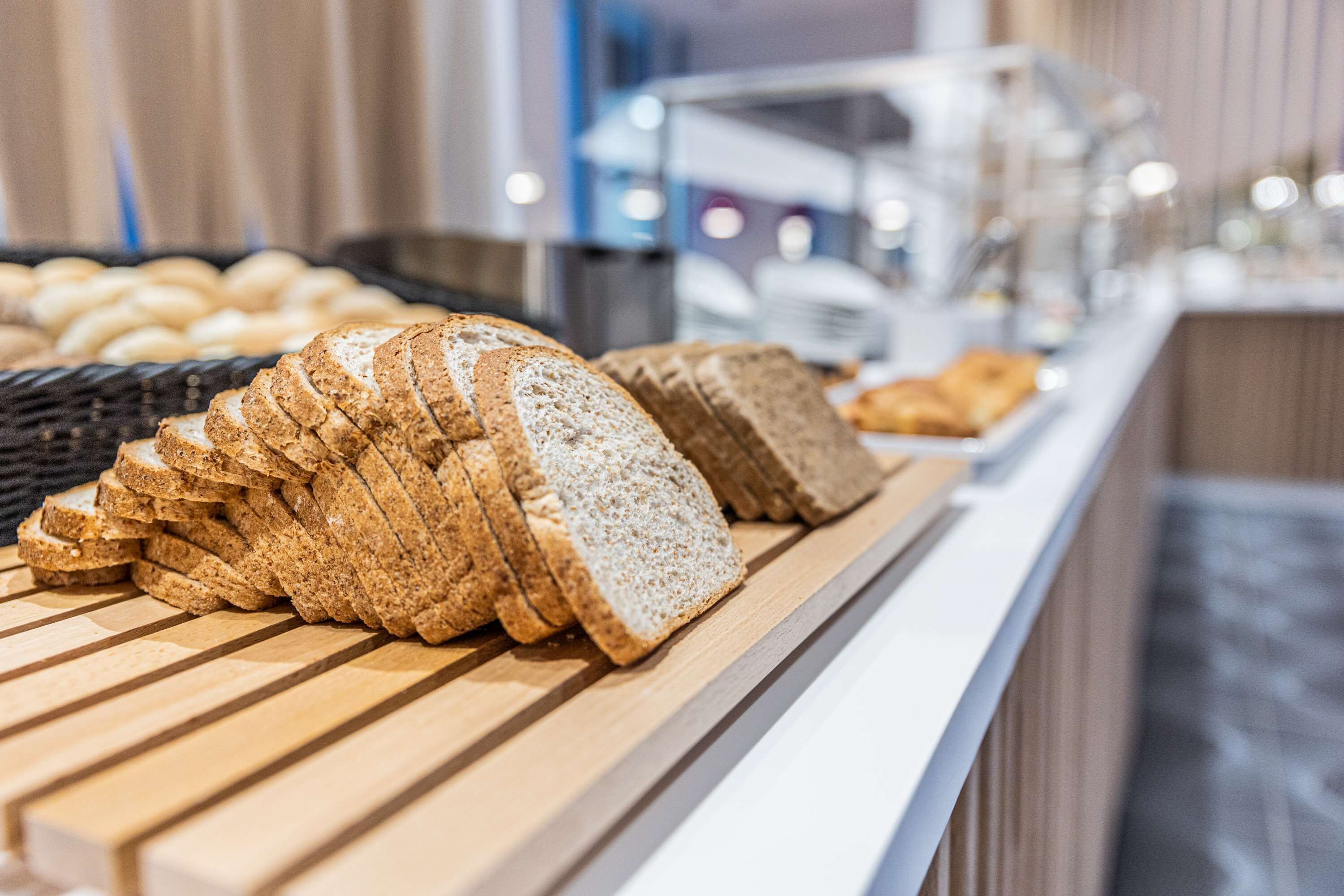 Verschillende soorten sneetjes brood op een houten toonbank in een bakkerij.