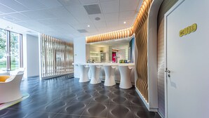 A modern hotel lobby with a reception desk, seating area, and a sign indicating the location of the WC. - Prize by Radisson, Antwerp City (Antwerp)