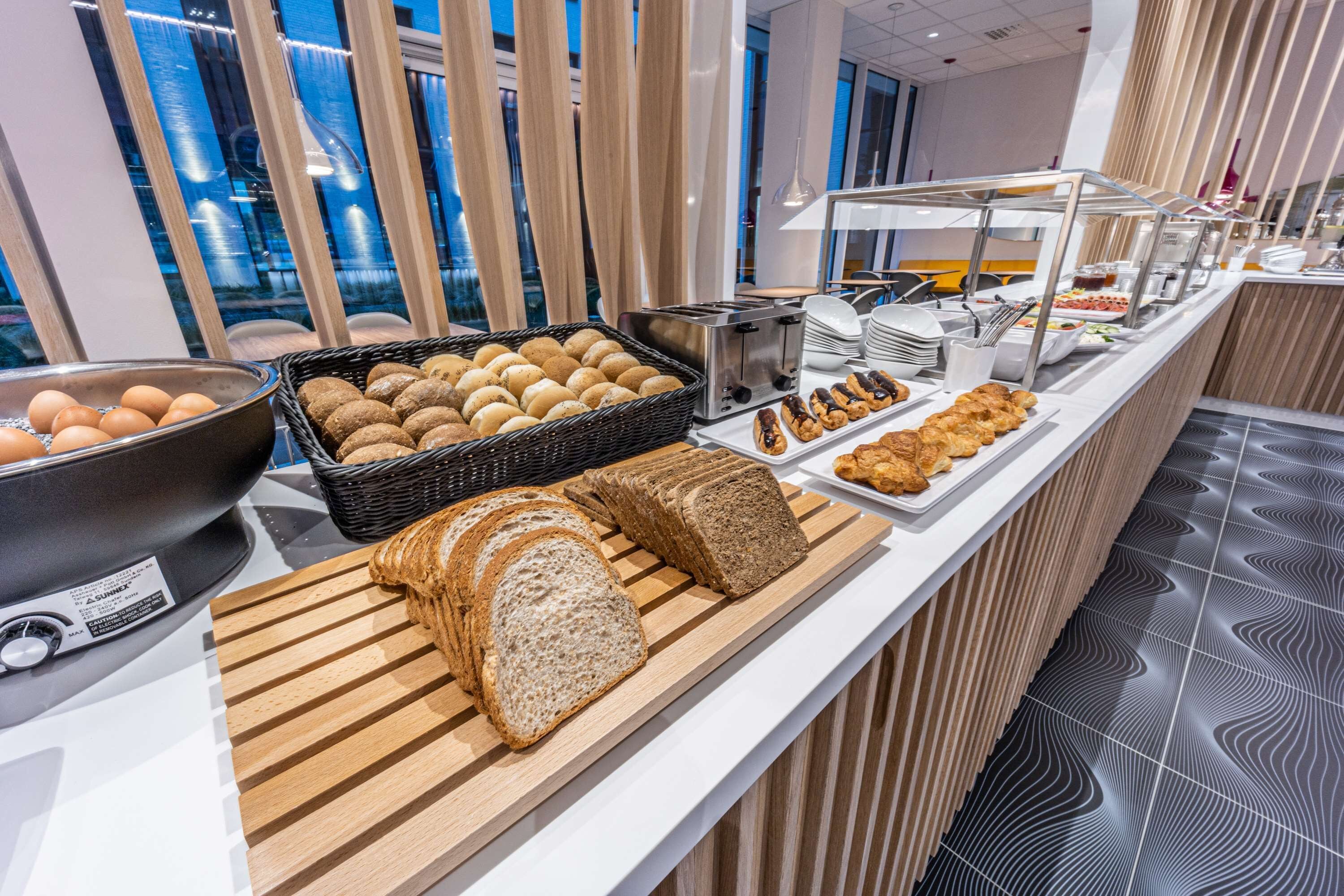 A buffet with various food items including bread, pastries, and eggs.