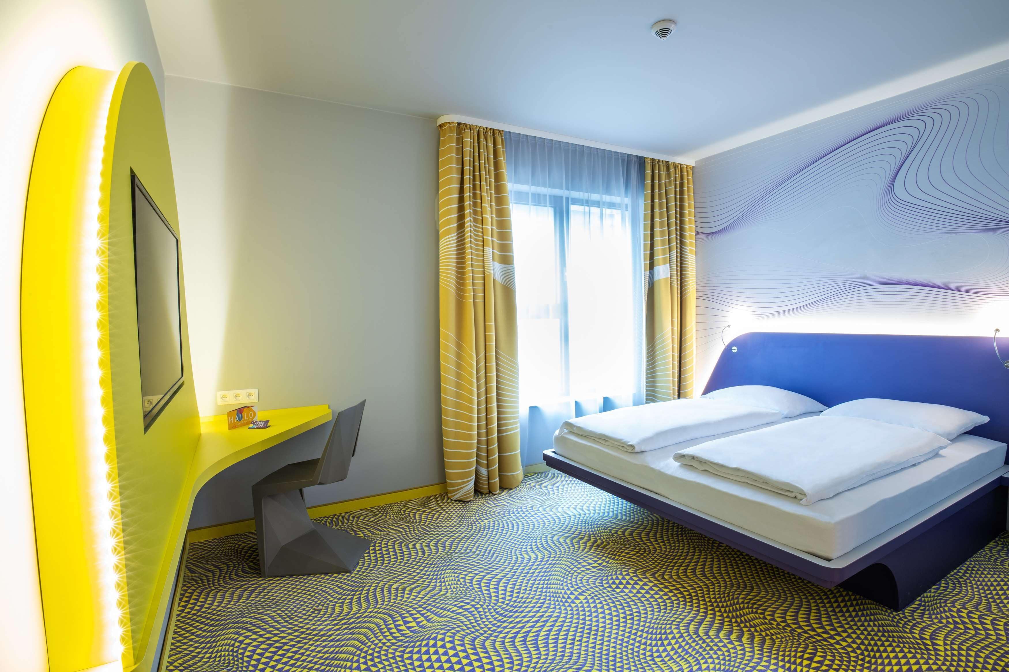 A hotel room with a bed, a desk, and a chair.