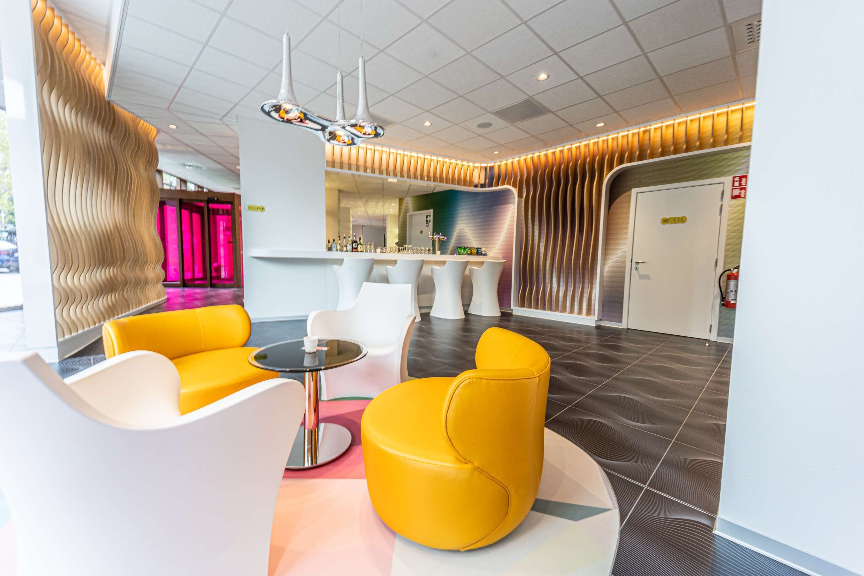 A modern lobby with a bar area, seating, and a reception desk.