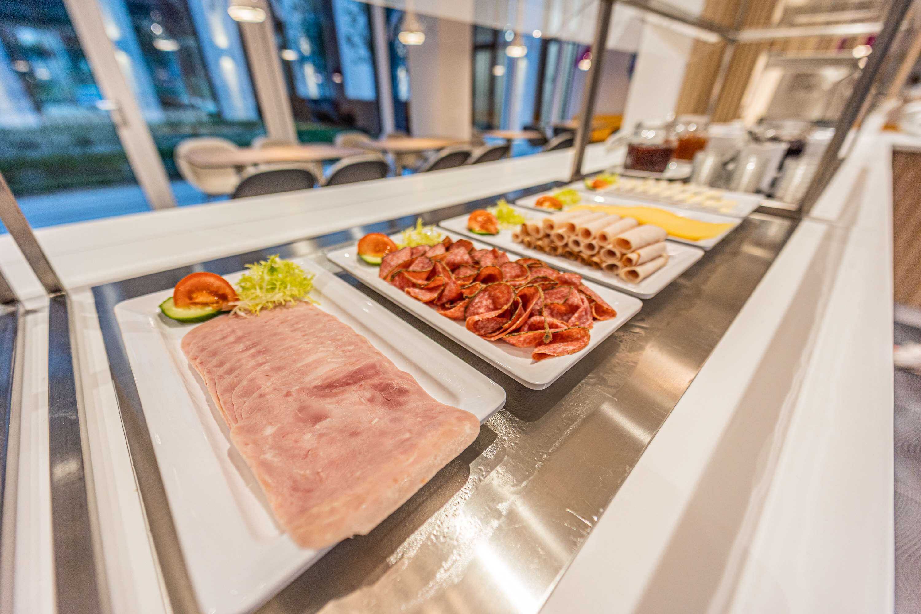 Ein Buffet mit verschiedenen Speisen, darunter Schinken, Pepperoni und Pasta.