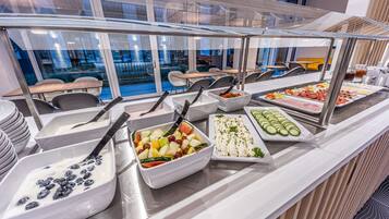 Un buffet proposant une variété de plats, notamment des fruits, des légumes et des viandes.