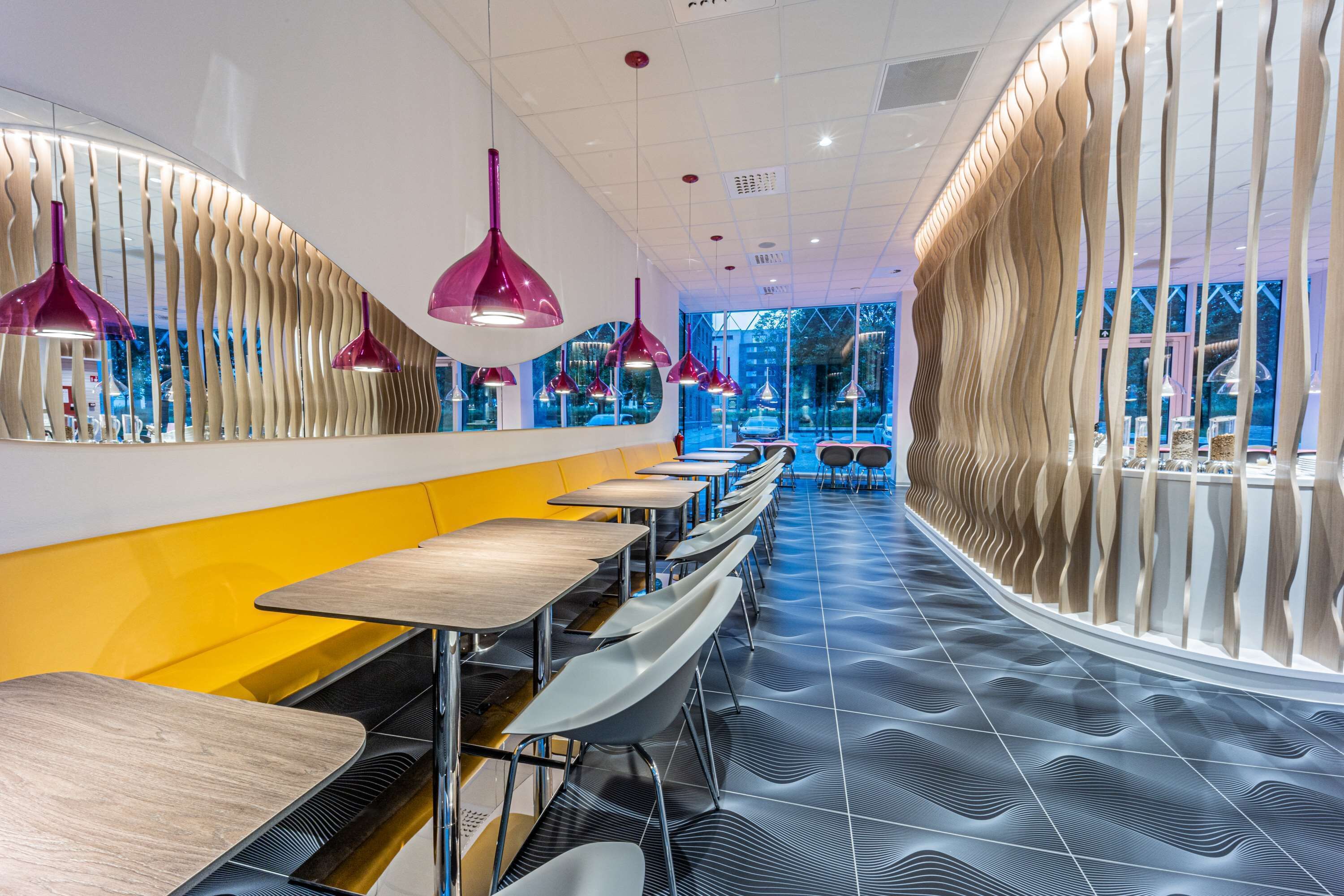 A modern restaurant with a curved seating area, pendant lighting, and a patterned floor.