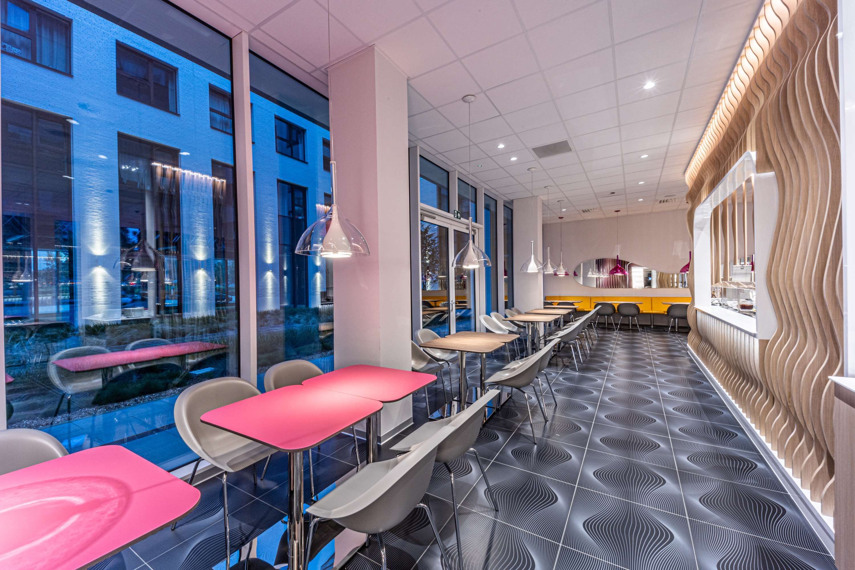 Un restaurante moderno con una barra larga, ventanas de vidrio transparente y un piso con diseño.