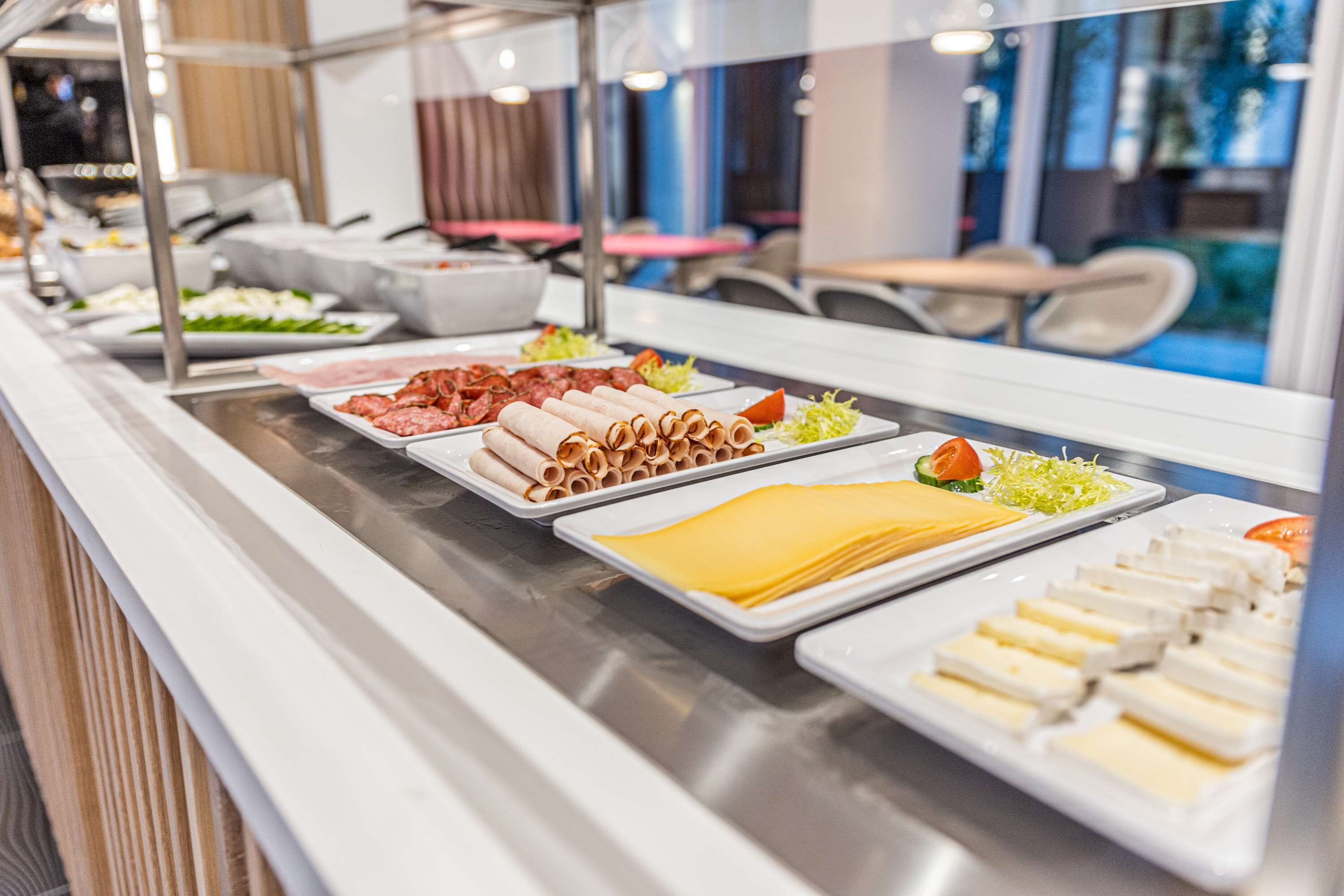 Een buffet met diverse gerechten, waaronder vlees, kazen en salades.