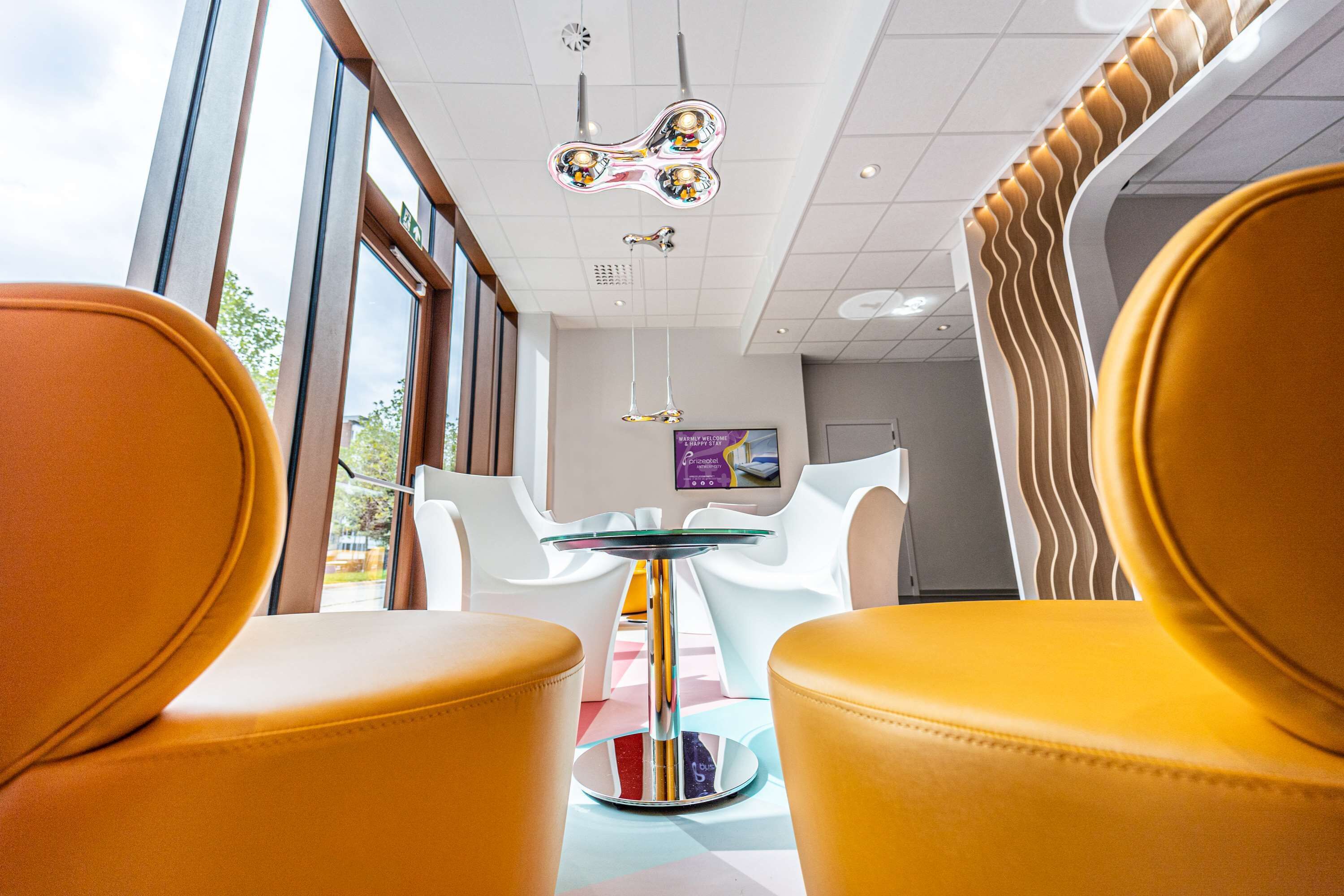 A modern interior with yellow chairs, a glass-top table, and a unique ceiling design.