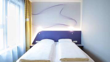 Quarto de hotel com cama, cortinas e uma parede com padrão ondulado.