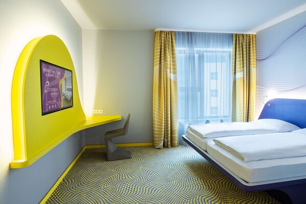 Una habitación de hotel con una cama, un escritorio y un cartel en la pared.