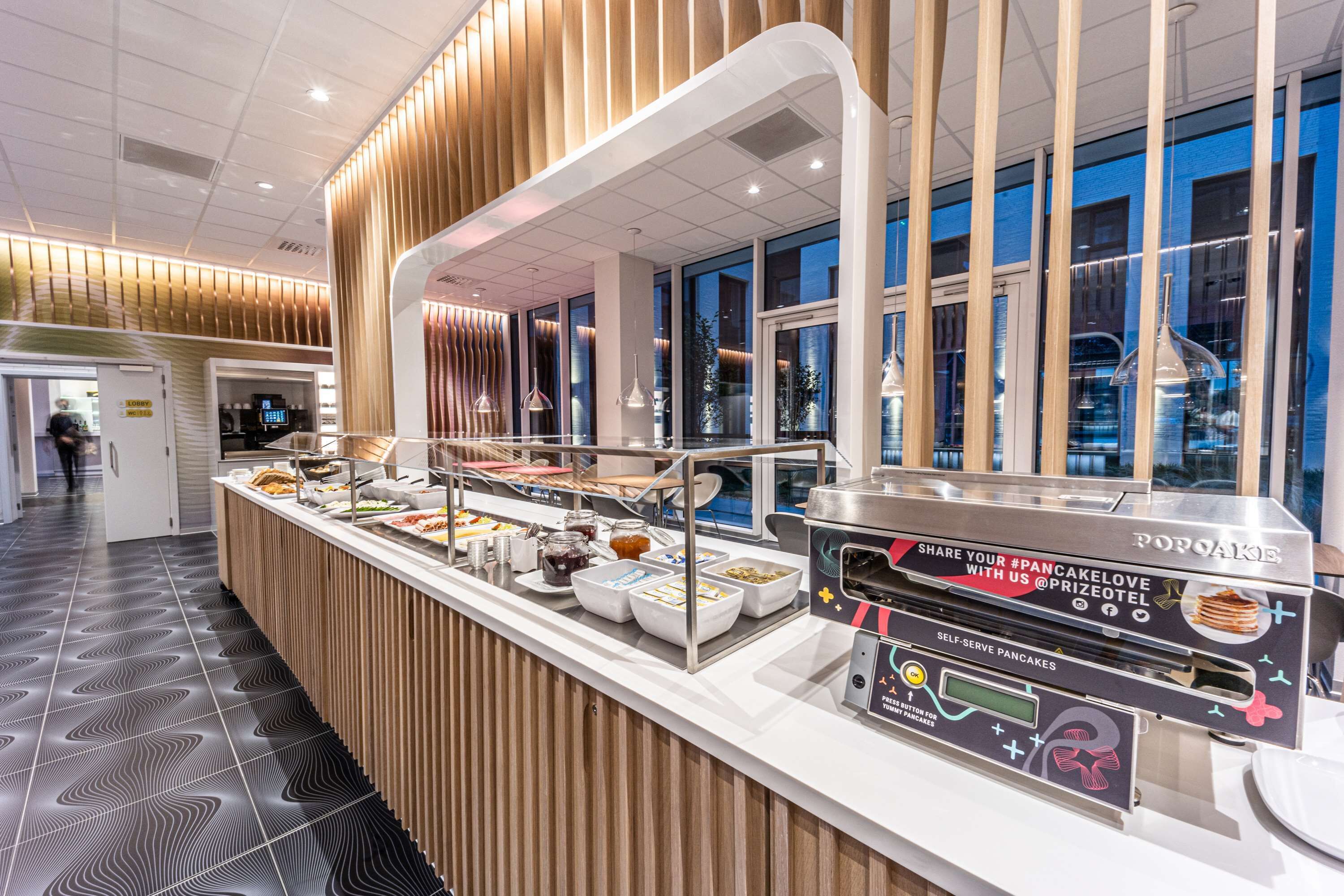 A self-serve breakfast station with various food options and a promotional display for a prize draw.