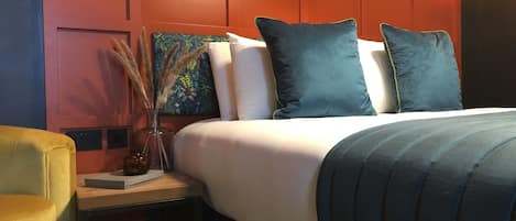 Una habitación de hotel con una cama, una mesita de noche, una lámpara y un cuadro.