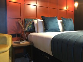 A hotel room with a bed, a nightstand, a lamp, and a painting.
