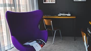 A modern office space with a purple chair, a desk with a turntable, and a poster on the wall.