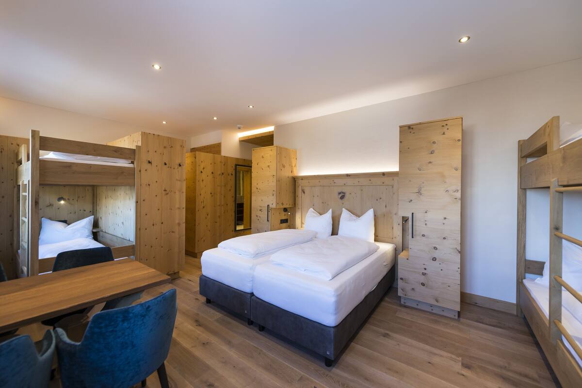 A modern bedroom with a large bed, wooden headboard, and a desk with a chair.