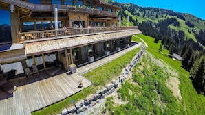 A wooden chalet with a balcony overlooking a mountainous landscape.