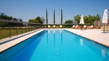 Una piscina al aire libre de temporada, tumbonas