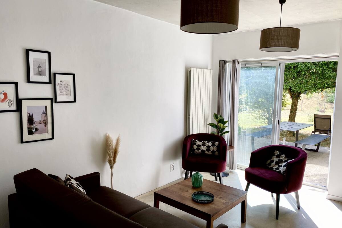 Ein modernes Wohnzimmer mit einer Couch, zwei Sesseln, einem Couchtisch und gerahmten Bildern an der Wand.