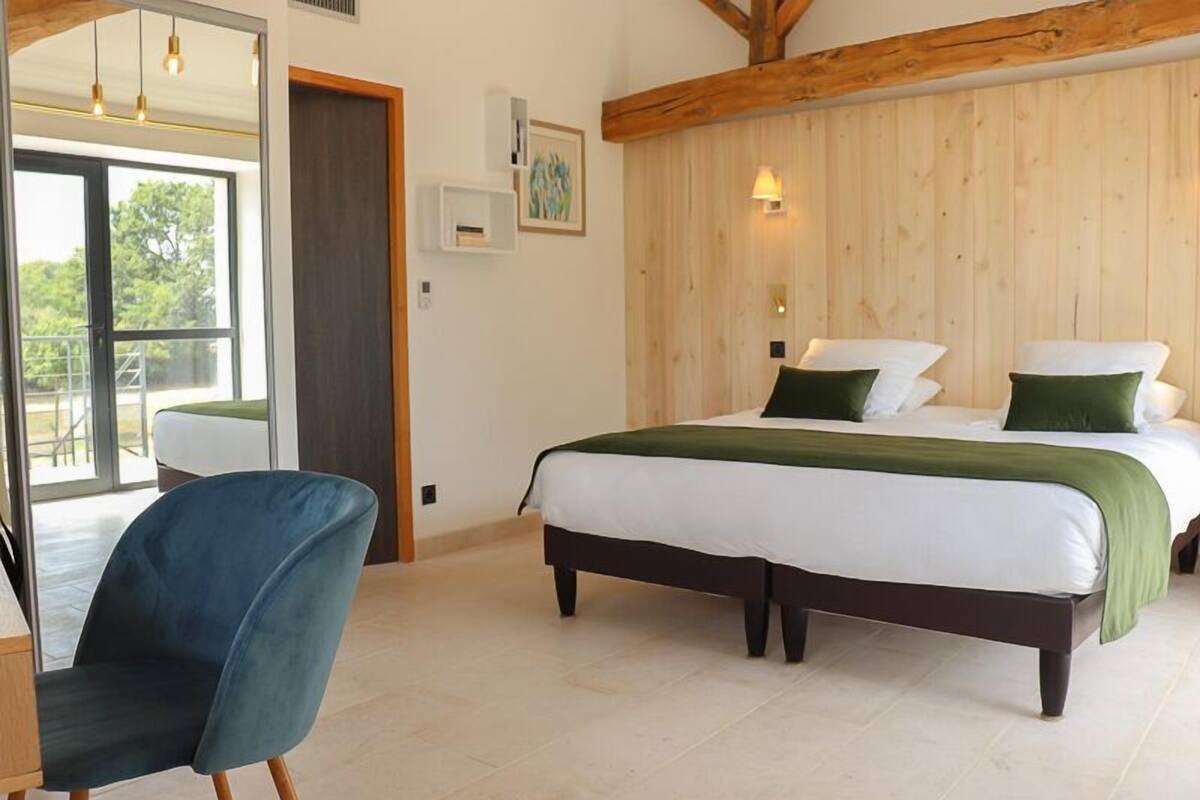 Ein Schlafzimmer mit einem Bett, einem Sessel und einer Holzbalkendecke.