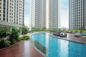 Ein moderner Pool mit Liegestühlen, umgeben von hohen Wohngebäuden.